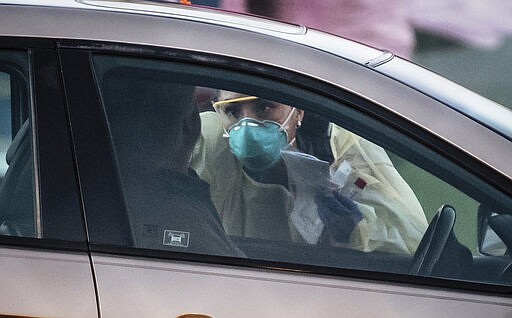 Medical personnel check a person at a mobile site for coronavirus testing across the street from Lovelace Hospital on Friday afternoon, March 13, 2020, in Albuquerque, N.M. (Roberto E. Rosales/The Albuquerque Journal via AP)