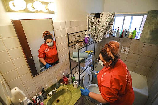 Lisa Loeffert, of Magic Maid Possible cleans a home in Las Cruces, N.M., on Wednesday, March 18, 2020. The cleaning service announced it will be offering free cleaning services to the elderly and the disabled who are the most vulnerable group of people to contract the novel coronavirus. (Nathan J. Fish/The Las Cruces Sun News via AP)