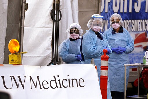 Medical personnel wait for a driver to pull up at a drive-through COVID-19 testing station for University of Washington Medicine patients Tuesday, March 17, 2020, in Seattle. The appointment-only drive-through clinic began a day earlier. Health authorities in Washington reported more COVID19 deaths in the state that has been hardest hit by the outbreak. (AP Photo/Elaine Thompson)