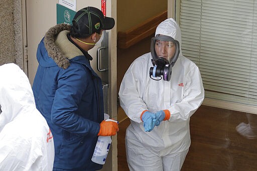 A Servpro cleaning worker wipes her hands Thursday, March 12, 2020, as she gets ready for a break from work cleaning inside the Life Care Center in Kirkland, Wash., near Seattle. The nursing home is at the center of the outbreak of the COVID-19 coronavirus in Washington state. For most people, the new coronavirus causes only mild or moderate symptoms. For some it can cause more severe illness. (AP Photo/Ted S. Warren)