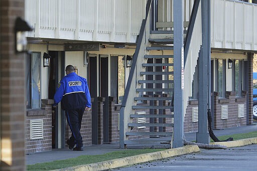 A security guard walks through a doorway at a former Econo Lodge motel that was purchased by King County to possibly house people under quarantine for the COVID-19 coronavirus, Monday, March 9, 2020, in Kent, Wash., near Seattle. (AP Photo/Ted S. Warren)