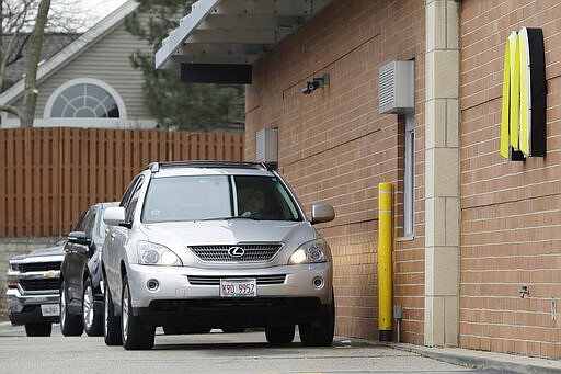 Customers wait for their drive-thru orders in their car at a McDonald's restaurant in Arlington Heights, Ill., Wednesday, March 18, 2020. All bars and restaurants in the state to have closed their dining rooms through March 30 due to coronavirus concerns. (AP Photo/Nam Y. Huh)