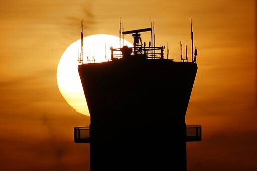 In this Tuesday, March 17, 2020 photo, the sun sets behind the FAA Control Tower at Chicago's Midway International Airport in Chicago. The FAA said Wednesday, March 18, 2020 that the tower is still closed for cleaning after several technicians tested positive Tuesday for coronavirus.. (AP Photo/Charles Rex Arbogast)