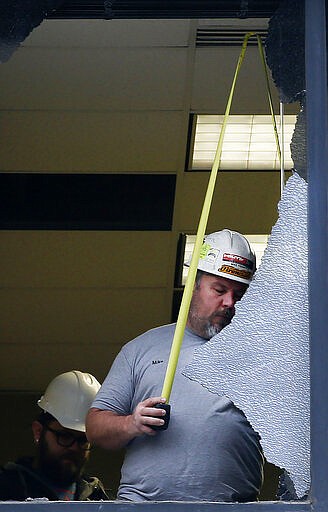 Mike Frampton, of City Glass, measures a broken window at the Maverik Base Camp building after a&#160;earthquake hit early on Wednesday, March 18, 2020.  A 5.7-magnitude earthquake has shaken Salt Lake City and many of its suburbs. The quake sent panicked residents running to the streets, knocked out power to tens of thousands of homes and closed the city's airport and its light rail system.  (Laura Seitz/The Deseret News via AP)