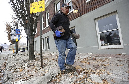 Fred Moesinger, owner of BTG Wine Bar and Caffe Molise in Salt Lake City, picks up bricks among debris that fell from his building after a earthquake hit early on Wednesday, March 18, 2020.  A 5.7-magnitude earthquake has shaken Salt Lake City and many of its suburbs. The quake sent panicked residents running to the streets, knocked out power to tens of thousands of homes and closed the city's airport and its light rail system. (Kristin Murphy/The Deseret News via AP)