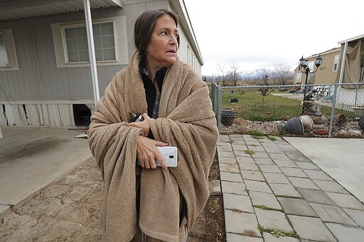 Tawnie Atkinson looks at damage to her neighbors mobile homes after a  earthquake in Salt Lake City on Wednesday, March 18, 2020. A 5.7-magnitude earthquake has shaken Salt Lake City and many of its suburbs. The quake sent panicked residents running to the streets, knocked out power to tens of thousands of homes and closed the city's airport and its light rail system.  (Jeffrey D. Allred/The Deseret News via AP)