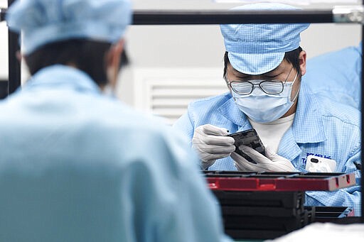 This March 11, 2020, photo released by Xinhua News Agency, shows workers at the assembly workshop of OPPO (Chongqing) Intelligence Technology Limited in Yubei District of southwest China's Chongqing Municipality. Factories in China, struggling to reopen after the coronavirus shut down the economy, face a new threat from U.S. anti-disease controls that might disrupt the flow of microchips and other components they need. For most people, the new coronavirus causes only mild or moderate symptoms. For some it can cause more severe illness. (Wang Quanchao/Xinhua via AP)