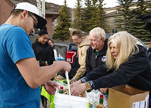 Gwyn Knowlton, right, and George Gordon, center right, along with other people from Gwyn's High Alpine pass out food supplies to Snowmass community members on Tuesday, March 17, 2020. (Kelsey Brunner//The Aspen Times via AP)