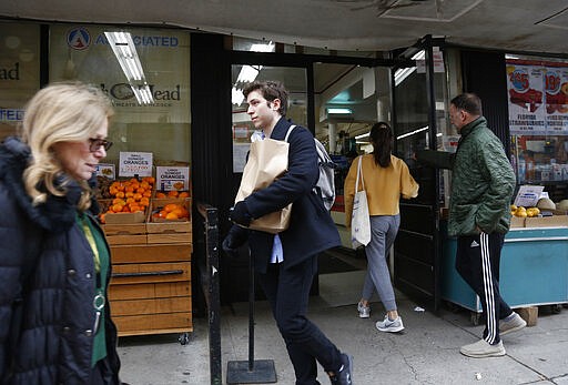 In this March 17, 2020, photo, Liam Elkind, 20, leaves the Associated Supermarket with a bag of groceries including salad ingredients and fresh produce for 83-year-old Carol Sterling, who is self-quarantined in her apartment in New York due to the coronavirus outbreak. Elkind, a junior at Yale, and his friend, Simone Policano, amassed about 1,300 volunteers in 72 hours to deliver groceries and medicine to older New Yorkers and others most vulnerable since the virus swept the city. They call themselves Invisible Hands, and they do something else in the process, provide some human contact and comfort, at a safe distance, of course. (AP Photo/Jessie Wardarski)