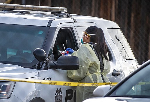 Medical personnel test patients including this Albuquerque Police officer at a mobile site for coronavirus testing across the street from Lovelace Hospital on Friday afternoon, March 13, 2020, in Albuquerque, N.M. (Roberto E. Rosales/The Albuquerque Journal via AP)