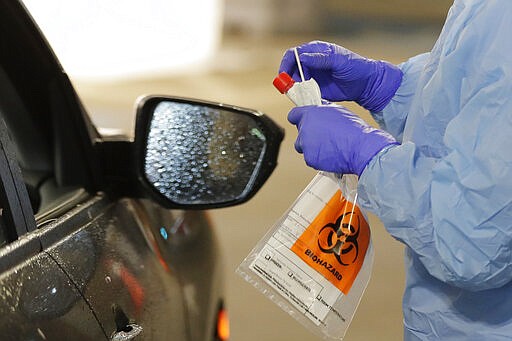 FILE - In this March 13, 2020, file photo, a nurse at a drive up COVID-19 coronavirus testing station, set up by the University of Washington Medical Center, holds a swab used to take a sample from the nose of a person in their car in Seattle. The federal government is rushing protective equipment to states for medical workers who will be on the front lines of the growing coronavirus pandemic. Washington state has received at least two shipments and needs more. At least in two other states, promised deliveries are falling far short of requests and even include expired items. (AP Photo/Ted S. Warren, File)