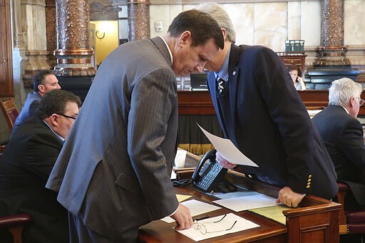 Kansas state Sen. Dennis Pyle, left, R-Hiawatha, confers with Sen. Eric Rucker, right, R-Topeka, during a Senate discussion of a resolution extending a state of emergency declared by Democratic Gov. Laura Kelly, in Topeka, Kan, Wednesday, March 18, 2020. Pyle added language declaring that Kelly can't confiscate guns or ammunition or prohibit their sale, even though she has not suggested such steps. (AP Photo/John Hanna)