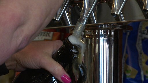 Tap room manager Rene Betancourt fills a growler with beer to go at the White Street Brewing Company in Wake Forest, N.C., on Tuesday, March 17, 2020. With bars ordered close due to coronavirus, brewers are making sure their customers can enjoy some fresh suds. (AP Photo/Allen G. Breed)