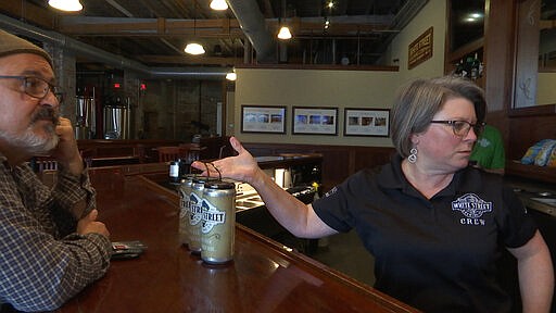 Tap room manager Rene Betancourt hands three &quot;crowlers&quot; of beer to Jim Judge at the White Street Brewing Company in Wake Forest, N.C., on Tuesday, March 17, 2020. With bars ordered close due to coronavirus, brewers are making sure their customers can enjoy some fresh suds. (AP Photo/Allen G. Breed)