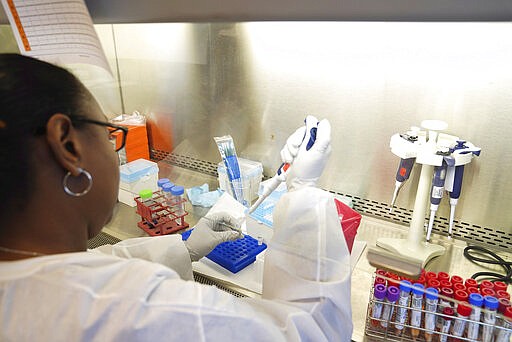 In a photo provided by the Mississippi State Department of Health, a department laboratory technologist extracts genetic material from a potential COVID-19 specimen Monday, March 16, 2020, at the department's lab in Jackson, Miss. (Mississippi State Department of Health, via AP)