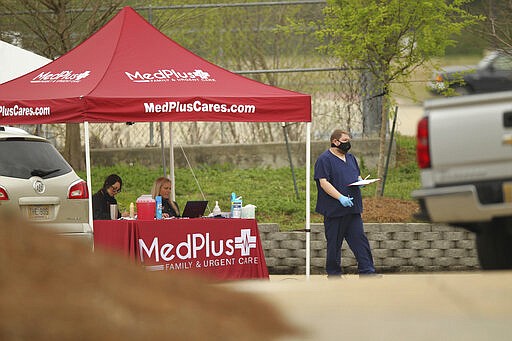 A medical worker makes his way to a vehicle  to conduct a drive through test for the novel coronavirus Wednesday, March 18, 2020, at the MedPlus facility on Barnes Crossing road in Tupelo, Miss. (Thomas Wells/The Northeast Mississippi Daily Journal via AP)