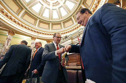 President Pro Tempore Dean Kirby, R-Clinton, left, and Sen. Philip Moran, R-Kiln, fist bump as they leave their chamber at the Capitol in Jackson, Miss., Wednesday, March 18, 2020. The Senate voted to adjourn until April 1, following suit of the House which adjourned Tuesday. The lieutenant governor and speaker of the House may delay a return to the Capitol at their own discretion. (AP Photo/Rogelio V. Solis)