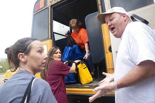 Teachers and school personnel place food onto buses at Sherman Avenue Elementary School as the Vicksburg Warren School District prepares to deliver meals to school aged children in Warren County, Miss., Wednesday, March 18, 2020.  (Courtland Wells/The Vicksburg Post via AP)