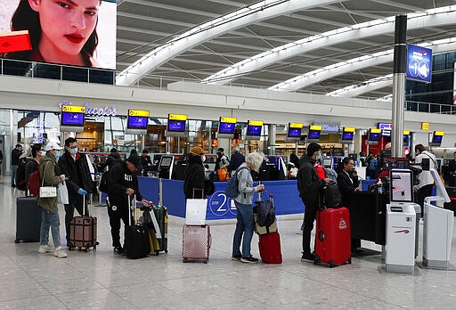 People queue at ticket machines at Heathrow airport in London, Wednesday, March 18, 2020. For most people, the new coronavirus causes only mild or moderate symptoms, such as fever and cough. For some, especially older adults and people with existing health problems, it can cause more severe illness, including pneumonia. (AP Photo/Frank Augstein)