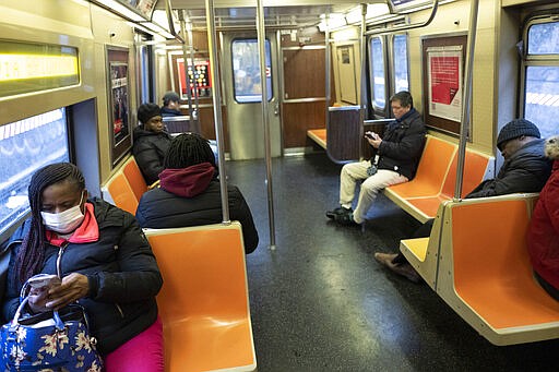 A woman wears a mask as she commutes during rush hour on a subway, Tuesday, March 17, 2020 in New York. The subway is normally crowded but many people are staying home out of concern for the spread of coronavirus. (AP Photo/Mark Lennihan)