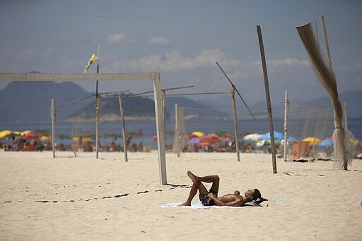 A man sunbathes on Copacabana beach in Rio de Janeiro, Brazil, Wednesday, March 18, 2020. Firemen have been blaring recordings that urge beachgoers to stay home as a preventive measure against the spread of the new coronavirus. The vast majority of people recover from the new virus.  (AP Photo/Silvia Izquierdo)