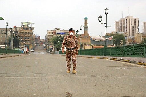 A federal police officer crosses an empty bridge over the Tigris River in Baghdad, Iraq, Wednesday, March 18, 2020. Iraq announced a weeklong curfew to help fight the spread of the virus. For most people, the virus causes only mild or moderate symptoms. For some it can cause more severe illness. (AP Photo/Hadi Mizban)