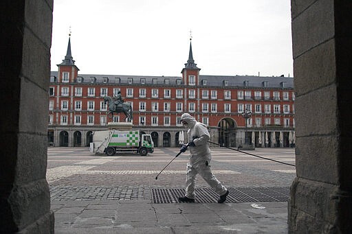 A cleaner worker cleans the pavement of Plaza Mayor square in Madrid downtown, Spain, Wednesday, March 18, 2020. Spain will mobilize 200 billion euros or the equivalent to one fifth of the country's annual output in loans, credit guarantees and subsidies for workers and vulnerable citizens, Prime Minister Pedro Sanchez announced Tuesday. For most people, the new coronavirus causes only mild or moderate symptoms. For some, it can cause more severe illness, especially in older adults and people with existing health problems. (AP Photo/Manu Fernandez)