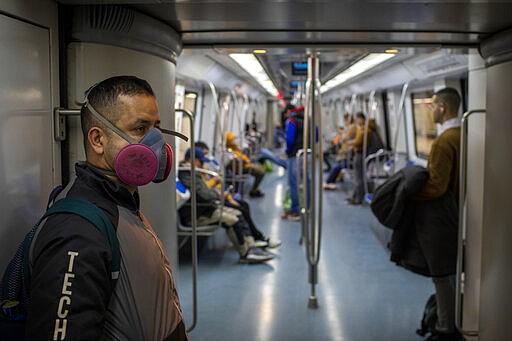 A man wearing a face mask travels by train in Barcelona, Spain, Wednesday, March 18, 2020. Spain will mobilize 200 billion euros or the equivalent to one fifth of the country's annual output in loans, credit guarantees and subsidies for workers and vulnerable citizens, Prime Minister Pedro S&aacute;nchez announced Tuesday. For most people, the new coronavirus causes only mild or moderate symptoms. For some, it can cause more severe illness, especially in older adults and people with existing health problems. (AP Photo/Emilio Morenatti)