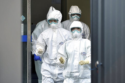 Medical staff members arrive for a duty shift at Dongsan Hospital in Daegu, South Korea, Wednesday, March 18, 2020. For most people, the new coronavirus causes only mild or moderate symptoms, such as fever and cough. For some, especially older adults and people with existing health problems, it can cause more severe illness, including pneumonia. (Lee Moo-ryul/Newsis via AP)