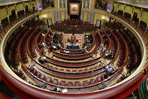 Spain's Prime Minister Pedro Sanchez, top, delivers a speech to explain measures under the state of emergency to an almost empty parliament while the majority of lawmakers follow the session online, in Madrid, Spain, Wednesday March 18, 2020. Spain will mobilize 200 billion euros or the equivalent to one fifth of the country's annual output in loans, credit guarantees and subsidies for workers and vulnerable citizens Pedro Sanchez announced earlier. For most people, the new coronavirus causes only mild or moderate symptoms. For some, it can cause more severe illness, especially in older adults and people with existing health problems. (Mariscal, Pool photo via AP)