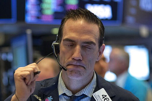 Stock trader Gregory Rowe works at the New York Stock Exchange, Wednesday, March 18, 2020 in New York. Global stock markets have sunk in a third day of wild price swings after President Donald Trump promised to prop up the U.S. economy through the coronavirus outbreak.(AP Photo/Mark Lennihan)