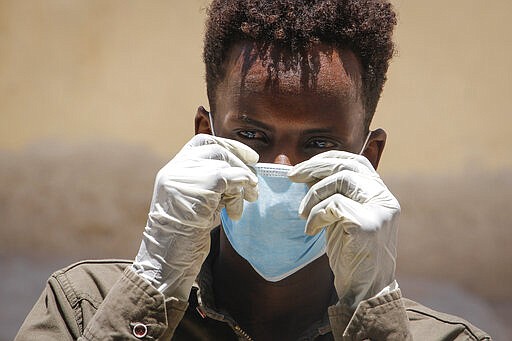 A Somali man wears a surgical mask and gloves on the street after after the government announced the closure of schools and universities and banned large gatherings, following the announcement on Monday of the country's first case of the new coronavirus, in the capital Mogadishu, Somalia Wednesday, March 18, 2020. For most people, the new coronavirus causes only mild or moderate symptoms such as fever and cough and the vast majority recover in 2-6 weeks but for some, especially older adults and people with existing health issues, the virus that causes COVID-19 can result in more severe illness, including pneumonia. (AP Photo/Farah Abdi Warsameh)