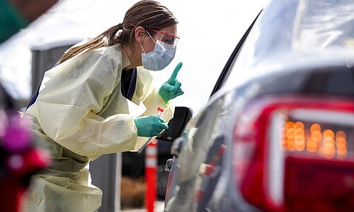 Ashley Layton, an LPN at St. Luke's Meridian Medical Center, communicates with a person before taking swab sample at a special outdoor drive-thru screening station for COVID-19   coronavirus Tuesday, March 17, 2020.  (Darin Oswald/Idaho Statesman via AP)