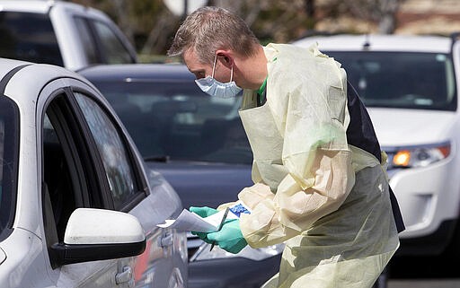 Nurse manager Cullen Anderson, RN, screens people in a line of cars waiting to be tested for COVID-19 coronavirus at a drive-thru testing station at St. Luke's Meridian Medical Center Tuesday, March 17, 2020 in Meridian Idaho. (Darin Oswald/Idaho Statesman via AP)