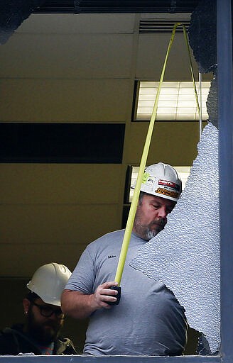 Mike Frampton, of City Glass, measures a broken window at the Maverik Base Camp building after a earthquake hit early on Wednesday, March 18, 2020.  A 5.7-magnitude earthquake has shaken Salt Lake City and many of its suburbs. The quake sent panicked residents running to the streets, knocked out power to tens of thousands of homes and closed the city's airport and its light rail system.  (Laura Seitz/The Deseret News via AP)