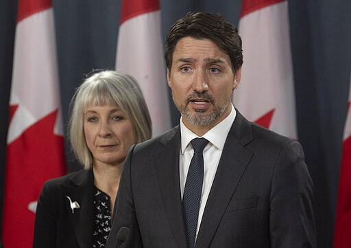 Minister of Health Patty Hajdu looks on as Prime Minister Justin Trudeau speaks during a news conference  in Ottawa, Wednesday March 11, 2020.  Canada is announcing $1 billion ($730 million) in funding to help health-care workers cope with the increasing number of new cases of coronavirus and to help Canadian workers who are forced to isolate themselves.  (Adrian Wyld/The Canadian Press via AP)