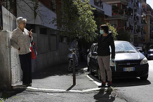 Enza Garzia, 79, left, talks at a distance with Paola Albano, in central Rome, March 11, 2020. (AP Photo/Alessandra Tarantino)