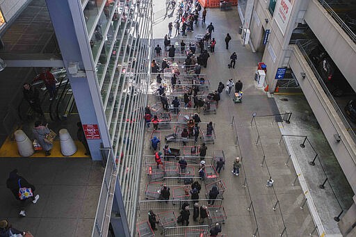 Customers make a line with the shopping carts at a local retail store, March 16, 2020 in New York. (AP Photo/Yuki Iwamura)