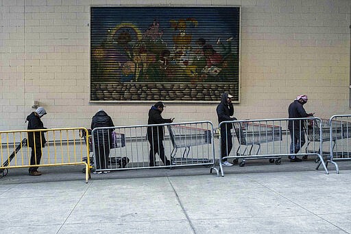 Customers make a line with shopping carts at a local retail store, March 16, 2020 in New York. (AP Photo/Yuki Iwamura)