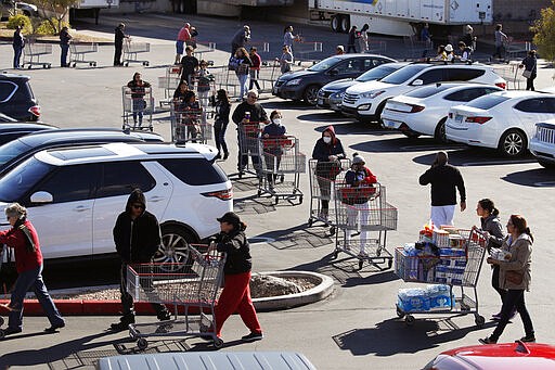 A line of people waiting to buy supplies amid coronavirus fears snakes through a parking lot at a Costco, March 14, 2020, in Las Vegas. (AP Photo/John Locher)