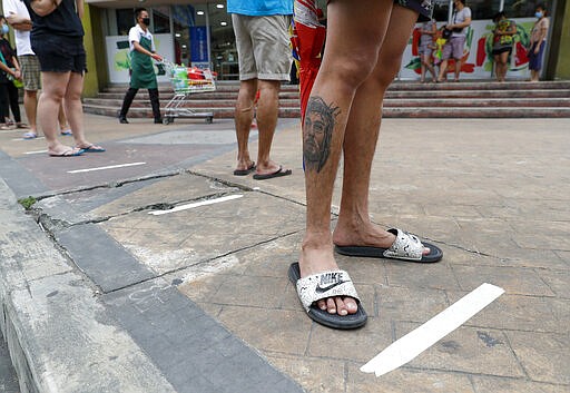 Residents step on measured tape placed outside a supermarket to practice social distancing as a precautionary measure against the spread of the coronavirus in Metro Manila, Philippines, March 17, 2020. (AP Photo/Aaron Favila)
