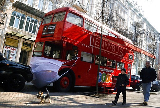 A man and a boy walk past a double-decker bus that is used as a cafe, symbolically wearing a face mask, in Kyiv, Ukraine, Wednesday, March 18. 2020. Ukraine has so far reported more then ten confirmed cases of the new virus and two deaths. Ukrainian government closed the country's border last week, shut down schools and banned public events, suspended public transportation and imposed fines for violating quarantine protocols.For most people, the new coronavirus causes only mild or moderate symptoms. For some it can cause more severe illness, especially in older adults and people with existing health problems.(AP Photo/Efrem Lukatsky)