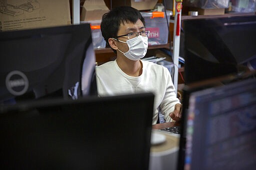 A worker wears a face mask as he works in the office of a tech company in Beijing, Wednesday, March 18, 2020. China's government has encouraged firms to open for business to restart the nation's economy as the number of new cases of coronavirus reported in the country continues to fall. The virus causes only mild or moderate symptoms, such as fever and cough, for most people, but severe illness is more likely in the elderly and people with existing health problems. (AP Photo/Mark Schiefelbein)