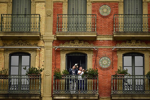 A young boy plays his trumpet from a balcony, in Pamplona, northern Spain, Wednesday, March 18, 2020. Spain will mobilize 200 billion euros or the equivalent to one fifth of the country's annual output in loans, credit guarantees and subsidies for workers and vulnerable citizens, Prime Minister Pedro Sanchez announced Tuesday. For most people, the new coronavirus causes only mild or moderate symptoms. For some, it can cause more severe illness, especially in older adults and people with existing health problems. (AP Photo/Alvaro Barrientos)