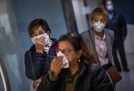 People wait their turn for a blood sample in a hallway of a hospital in Barcelona, Spain, Wednesday, March 18, 2020. Spain will mobilize 200 billion euros or the equivalent to one fifth of the country's annual output in loans, credit guarantees and subsidies for workers and vulnerable citizens, Prime Minister Pedro S&aacute;nchez announced Tuesday. For most people, the new coronavirus causes only mild or moderate symptoms. For some, it can cause more severe illness, especially in older adults and people with existing health problems. (AP Photo/Emilio Morenatti)