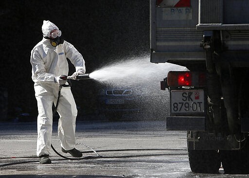 A worker wearing protective gear sprays disinfectant on a truck before entering the area most of infected with coronavirus in the country, at the town of Debar, in the western part of North Macedonia, on Wednesday, March 18, 2020. While expecting the President to declare the state of emergency, North Macedonia has closed borders for foreign nationals to enter, shut down two country's airports, restaurants, bars, schools, universities, kindergartens and constantly appeal people to stay at home to slow the spread of the coronavirus outbreak. The vast majority of people recover from the new coronavirus. According to the World Health Organization, most people recover in about two to six weeks, depending on the severity of the illness. (AP Photo/Boris Grdanoski)