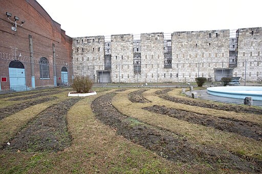 In this Feb. 13, 2020 photo, stone walls of a former cell block stand behind a garden used by inmates at Sing Sing Correctional Facility in Ossining, N.Y. Busting out of Sing Sing has been a dream of inmates since cell doors started clanging shut along the Hudson River in the 1820s. Now there's a plan to usher visitors inside the high walls of the prison famous as a go-to destination for gangsters, Hollywood stars and inmates condemned to the electric chair. (AP Photo/Mark Lennihan)