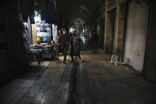 In this Tuesday, March 17, 2020, photo, people walk through the mostly closed Tehran's Grand Bazaar, Iran. The new coronavirus ravaging Iran is cutting into celebrations marking the Persian New Year, known as Nowruz. (AP Photo/Vahid Salemi)