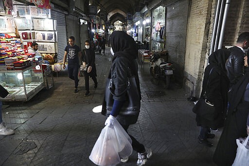 In this  Tuesday, March 17, 2020, photo, shoppers walk through the mostly closed Tehran's Grand Bazaar, Iran. The new coronavirus ravaging Iran is cutting into celebrations marking the Persian New Year, known as Nowruz. (AP Photo/Vahid Salemi)