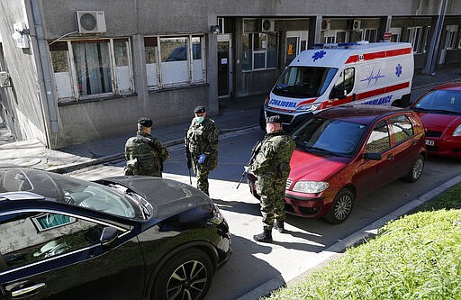 In this photo taken Monday, March 16, 2020, Serbian Army soldiers stand guard outside the Clinic for Infectious and Tropical Diseases in Belgrade, Serbia. Although the global COVID-19 pandemic has not hit Eastern and Central Europe with such a force compared to Italy, Spain and France, health officials throughout the region are sounding alarm about the lack of medical staff, facilities, equipment and enough hospital beds to handle several virus outbreaks simultaneously. For most people, the new coronavirus causes only mild or moderate symptoms. For some it can cause more severe illness. (AP Photo/Darko Vojinovic)